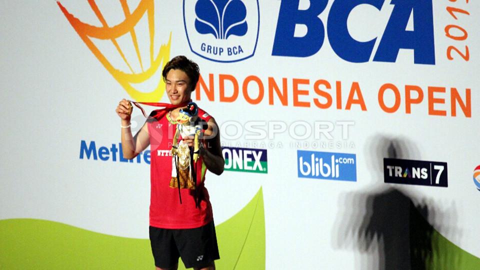 Kento Momota tersenyum bahagia usai menerima medali dan hadiah. - INDOSPORT